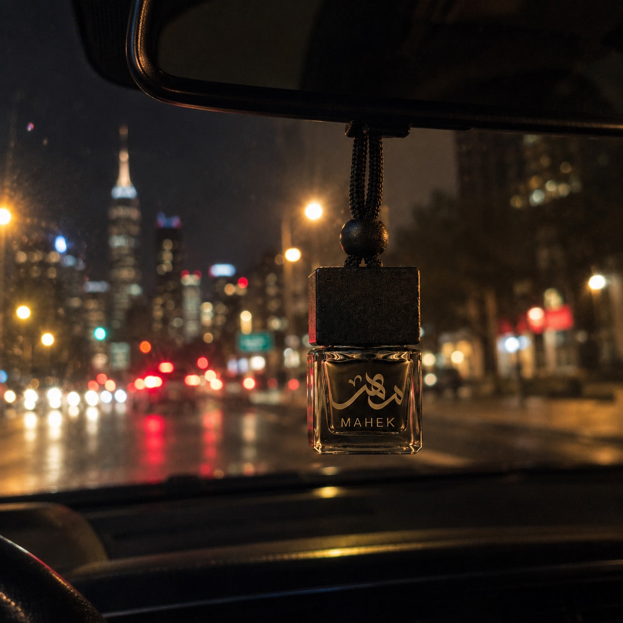 Mahek car diffuser hanging from a rearview mirror at night